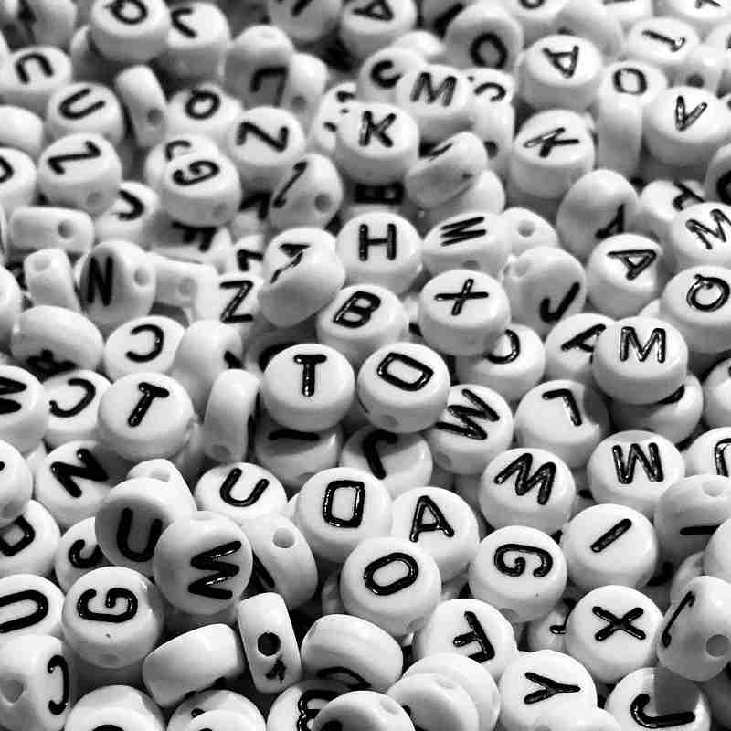 A jumble of black letters on white beads to inspire proofreading and editing.