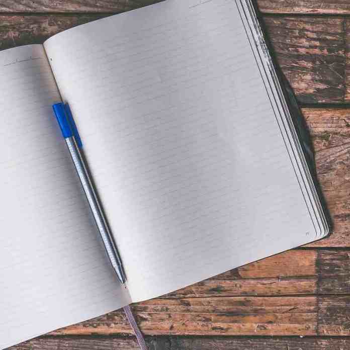 Open notebook on classic, rustic, wooden table waiting for your story ideas inspired by a writing prompt from Gail Owen writer.