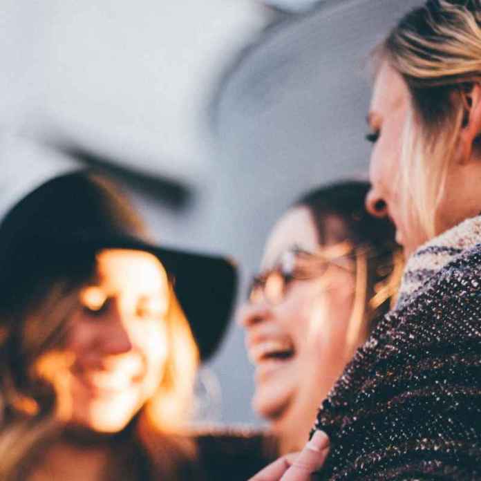 Three friends in conversation, their dialogue making them laugh together.